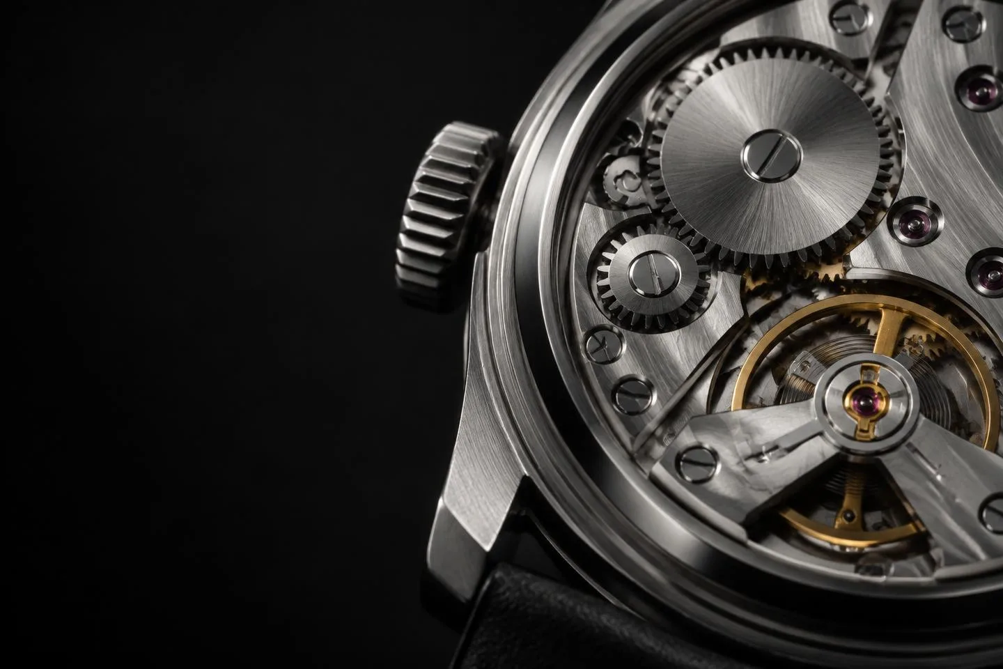 Macro detail of a mechanical luxury watch movement with brushed gears and a gold balance wheel